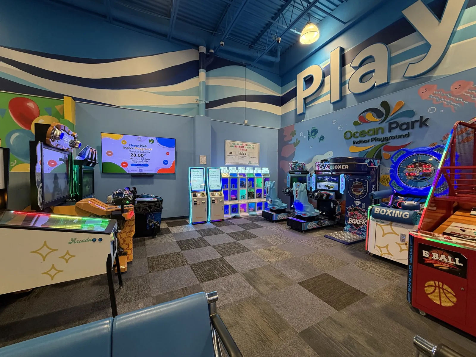 A full arcade installation with driving games, prize lockers, air hockey, and basketball at an indoor playground
