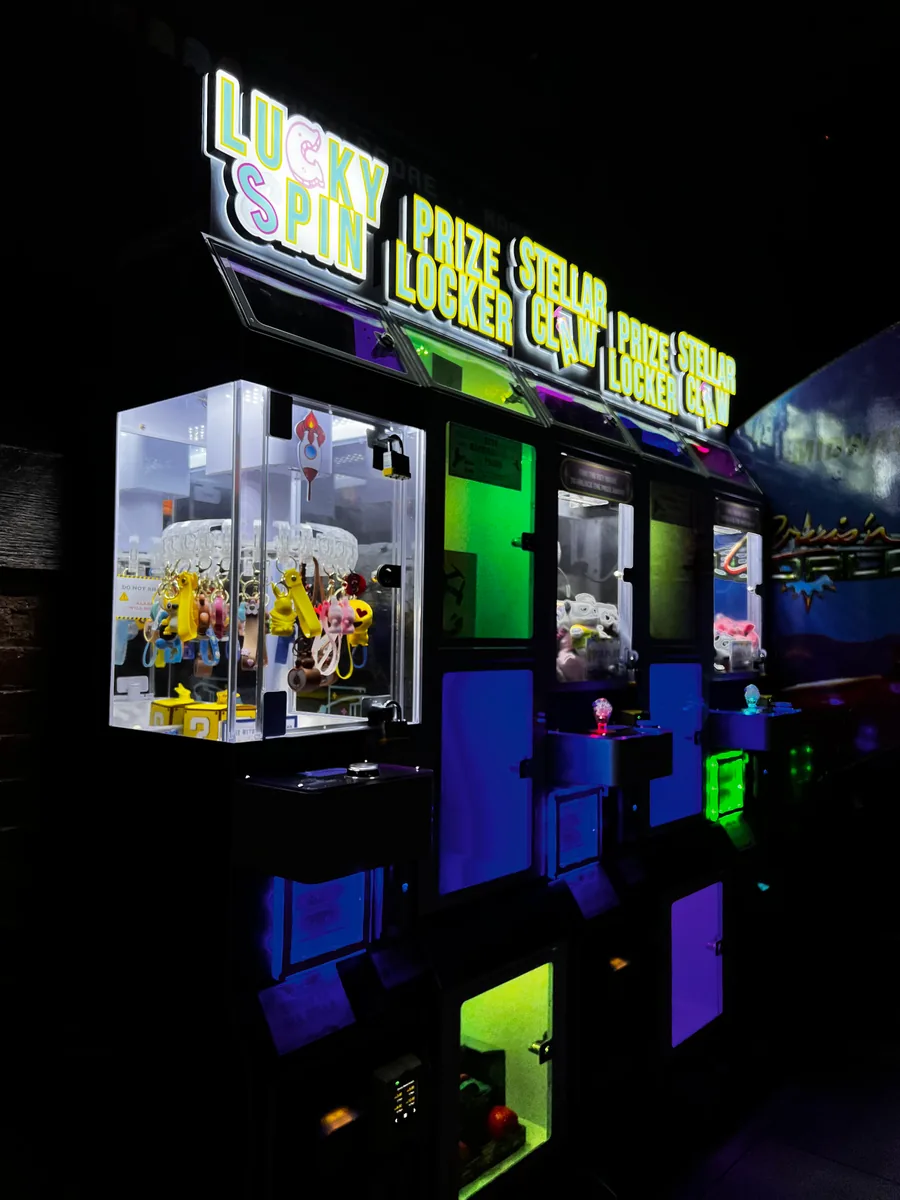 A row of five illuminated Lucky Spin, Prize Locker, and Stellar Claw machines in an entertainment venue