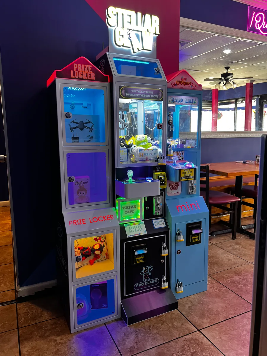 A Pro Claws prize locker and two claw machines installed beside a restaurant seating area