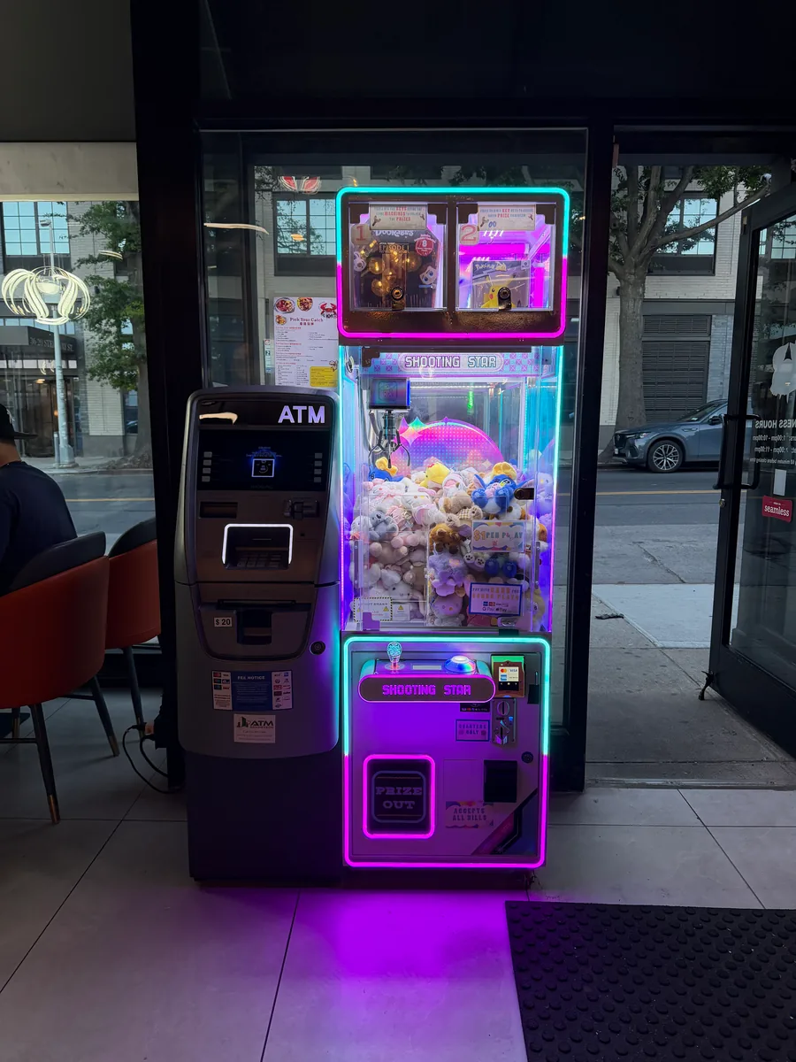 A single Shooting Star claw machine beside an ATM near a venue entrance